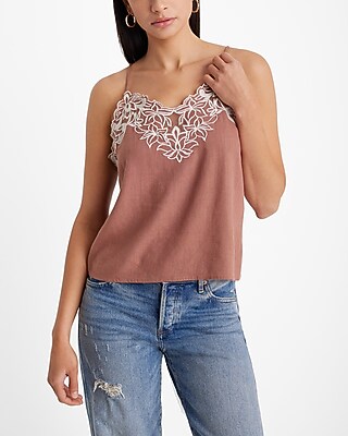 A woman wearing a pink tank top with white floral details at the top